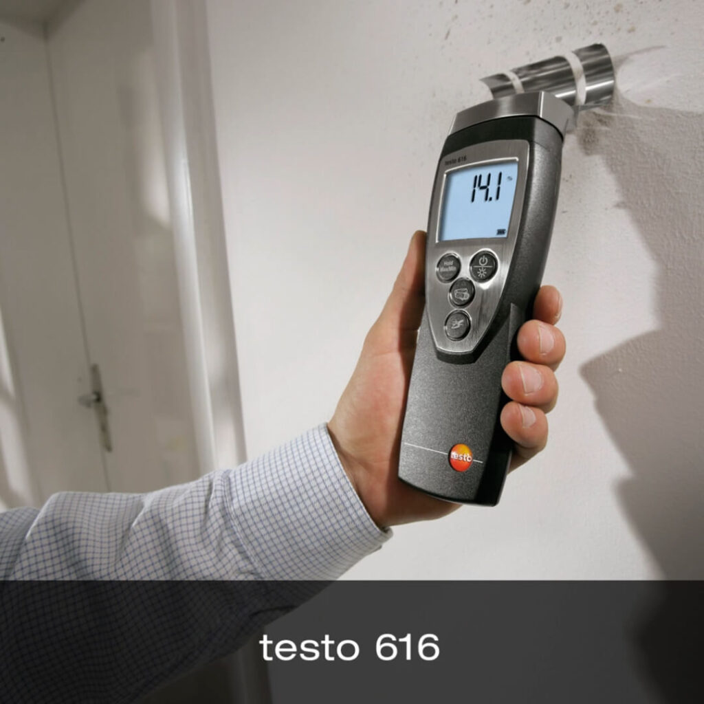 A person holds the Testo 616 Material Moisture Meter against a wall to measure the moisture content. A label at the bottom of the image reads "testo 616". 