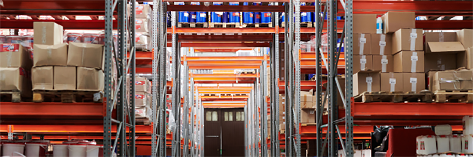 A warehouse with shelves reaching to the ceiling with cardboard boxes piled on top. 