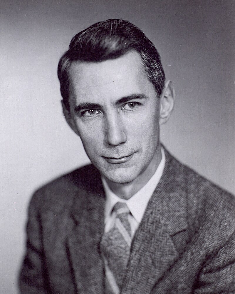 Forward-facing black and white photo portrait of Claude Shannon in a suit and tie. 