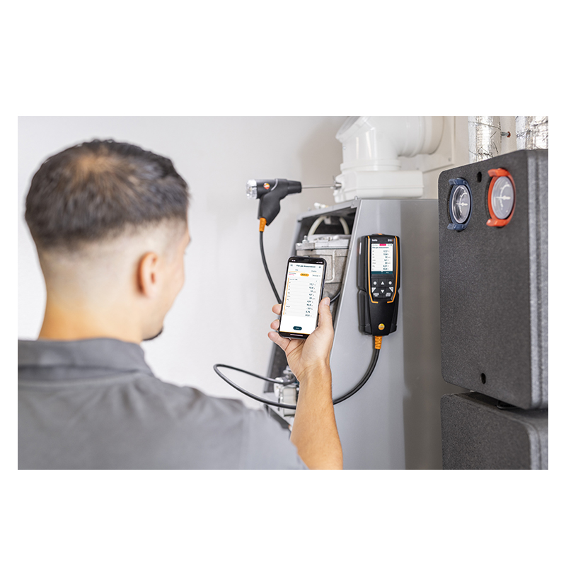 A man uses a Testo 310 and his smartphone with the Testo Smart App installed to test a boiler