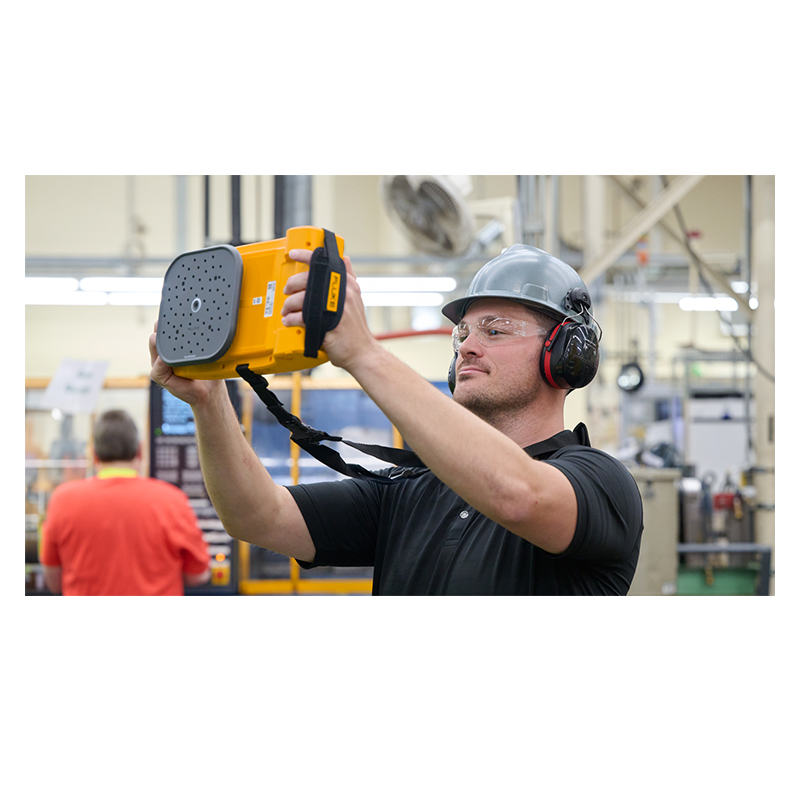 A man in a hardhat and earmuffs holds the ii915 up in front of him.