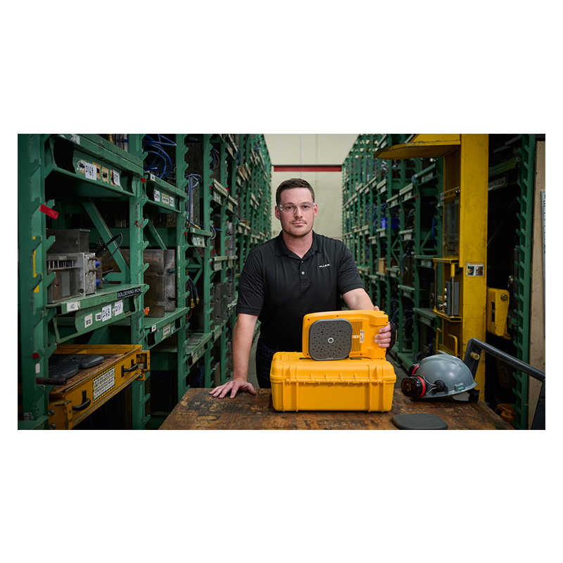 A man stands in a warehouse in front of him the Fluke ii915 is on a table