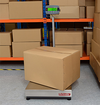 Ohaus Defender weighing a box in a warehouse.